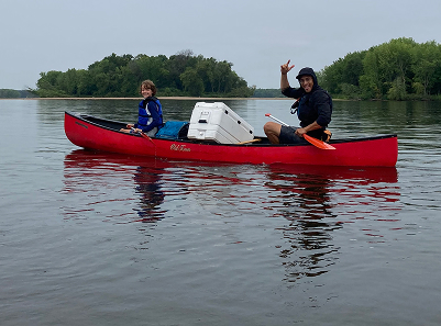 photo of two people waving from canoe on river